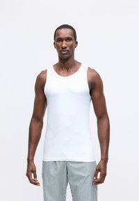 Balti bezpiedurkņu krekls, izgatavots no gludas, vieglas auduma, ar apaļu kakla izgriezumu un pieguļošu siluetu.