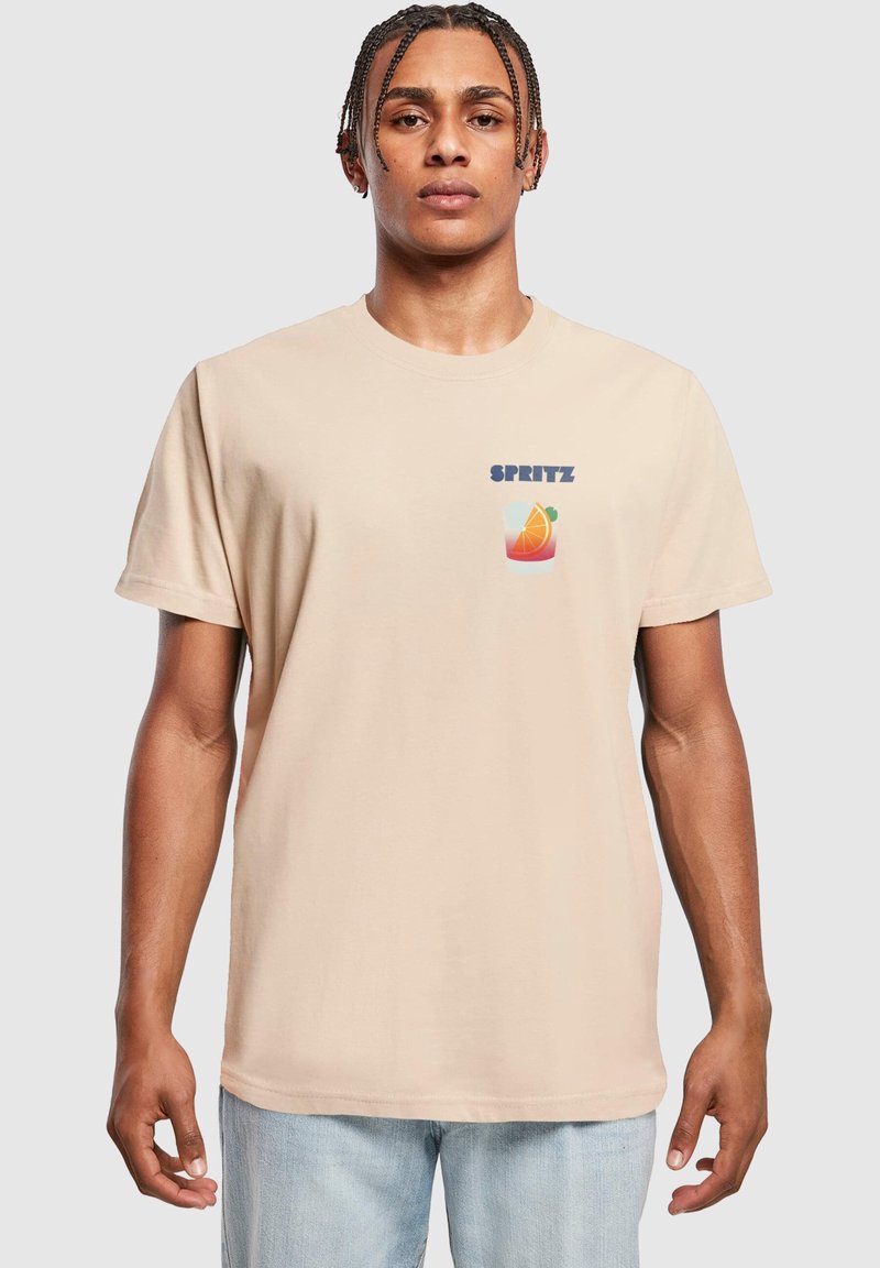 Beige cotton t-shirt featuring "SPRITZ" text and a colorful drink graphic on the left chest. Short sleeves and standard fit.