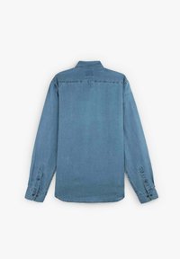 Camicia di denim azzurro chiaro a maniche lunghe con polsini abbottonati e colletto, esposta distesa di schiena su uno sfondo bianco.