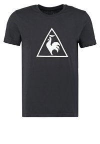 Svart t-shirt med kort ärm som har en vit triangulär logotyp av en tupp, tillverkad av mjukt tyg med regular fit.