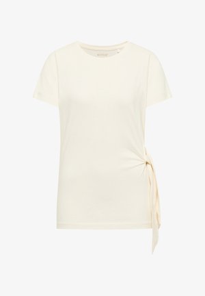 Top crema de manga corta con escote redondo, con detalle de lazo lateral en la cadera derecha, confeccionado en tela suave.