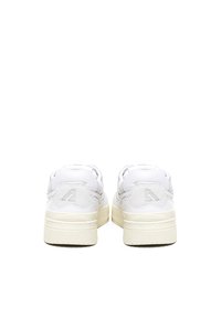 Zapatillas blancas con un acabado de cuero suave, que cuentan con un tacón elevado, un cuello acolchado y una suela de goma texturizada de color crema.