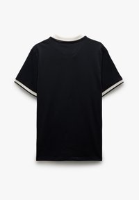 Musta lyhythihainen t-paita, jossa on pyöreä pääntie, ja joka sisältää kontrastiväriset valkoiset yksityiskohdat kauluksessa ja hihoissa. Pehmeää puuvillamateriaalia.