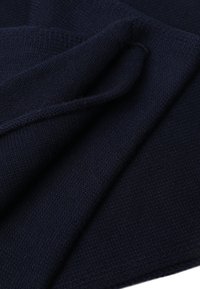 Mornarsko plava pletena tkanina s mekanom teksturom, s glatkim, ujednačenim uzorkom i slojevima presavijenim koji prikazuju debljinu i toplinu materijala.