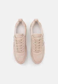 Ljust rosa mockaskor med rund tå, metalliska accenter på sidan och beige snören. Har en texturerad sula för grepp.