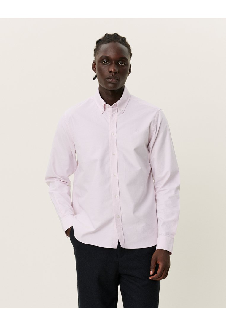 Ljusrosa långärmad skjorta med knappar i bomull, med en krage och en enkel bröstficka. Slät textur med en avslappnad passform.