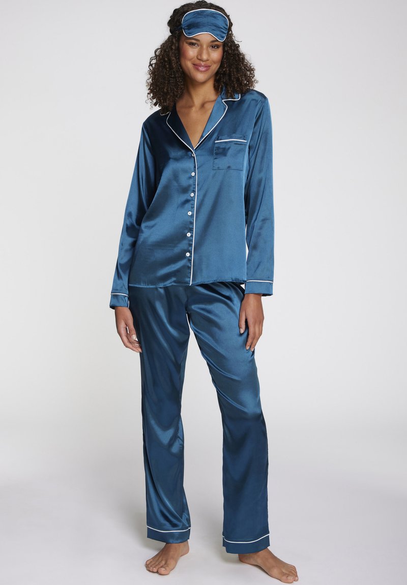 Blaue Satin-Zweiteiler-Pyjama-Set mit weißen Paspeln, bestehend aus einem Langarmhemd mit Knopfleiste und geraden Hosen, ergänzt durch eine passende Augenmaske.