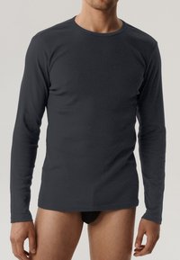 Koszula z długim rękawem wykonana z ciemnoszarego materiału, z okrągłym dekoltem i dopasowanym krojem. Gładka tekstura, minimalistyczny design bez widocznych wzorów.