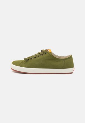 Zapatillas de lona verdes con punta redonda, suela de goma y entresuela blanca. Cuenta con seis ojetes y un pequeño acento amarillo cerca de la lengüeta.