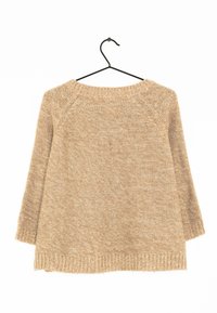 Beige stickad tröja med långa ärmar, rundad halsringning och ribbad fåll. Tyget har ett texturerat, grovt stickmönster. Hänger på en svart galge.