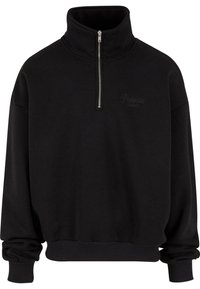 Svart quarter-zip genser laget av mykt stoff, med høy krage, ribbede mansjetter og en diskret logo i broderi.