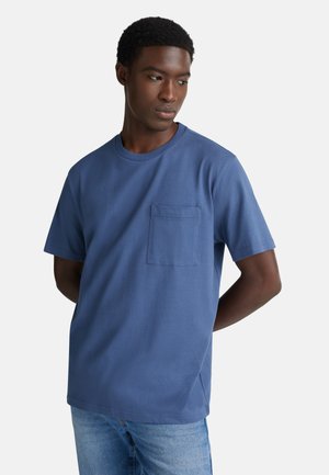 T-shirt di cotone blu con maniche corte, colletto girocollo e taschino sul petto. Il tessuto ha una superficie liscia e una vestibilità comoda.