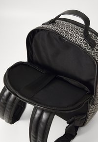 Crna i siva ruksak s geometrijskim uzorkom, s patentnim zatvaračem na vrhu, podstavljenim trakama i prostranim unutrašnjim dijelom podijeljenim tkanim razdvajačem.