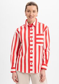 Red and white striped button-up shirt with a collar, long sleeves, and a front pocket. Fabric appears smooth with structured design.