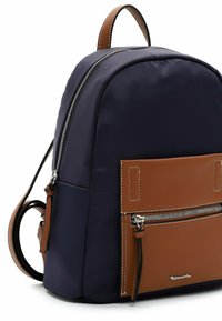 Marineblaue Stoff-Rucksack mit einer Fronttasche aus braunem Leder, silbernen Reißverschlüssen und einem Griff an der Oberseite. Verfügt über Kontrastnähte und ein Markenlogo.