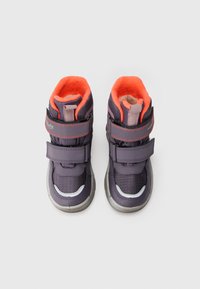 Une paire de bottes d'hiver pour enfants grises et oranges, avec deux sangles Velcro chacune, vue d'en haut sur un fond blanc.