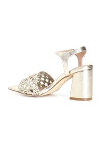 Goldene Sandalen mit Absatz, die ein geflochtenes Riemendesign und einen Knöchelverschluss besitzen. Sie verfügen über einen stabilen Absatz und ein glattes metallisches Finish.