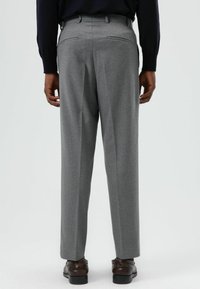 Grijze op maat gemaakte broek met een gladde textuur, voorzien van twee achterzakken en een recht model, gedragen met bruine schoenen.