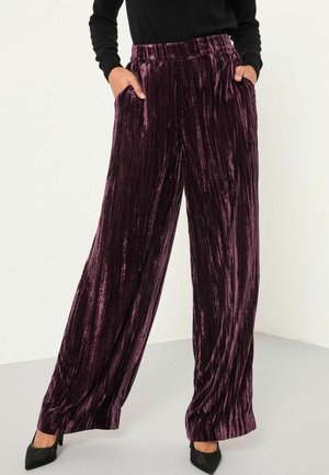 Plüschige, weit geschnittene Hosen aus tiefem Pflaumenvelours mit vertikalen Streifen, ausgestattet mit einem elastischen Bund und seitlichen Taschen.