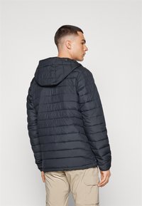 Zwarte donsjas met een horizontaal gestikt ontwerp en een capuchon. Gemaakt van geïsoleerd materiaal en een relaxte pasvorm, met zichtbare stiksels.