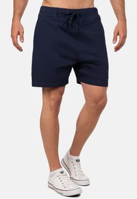 Pantaloni corti da uomo blu navy realizzati in tessuto misto cotone, con cintura elasticizzata e cordino, e tasche laterali; design semplice.