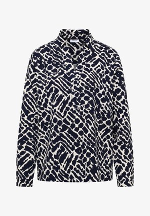 Chemise boutonnée bleu marine et blanche avec un motif abstrait d'animaux, manches longues et col avec un ourlet tombant.