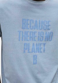 Camiseta de algodón azul claro con texto en negrita, ligeramente más oscuro, que dice "PORQUE NO HAY UN PLANETA B". Diseño clásico de cuello redondo.