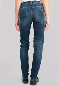Jeans skinny de mezclilla azul oscuro con una cintura de altura media, que cuentan con tres bolsillos, detalles de costura sutiles y una textura suave.