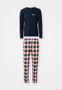 Camicia a maniche lunghe in cotone blu navy con taschino sul petto, abbinata a pantaloni da pigiama a quadri rossi, verdi e bianchi in un tessuto morbido.