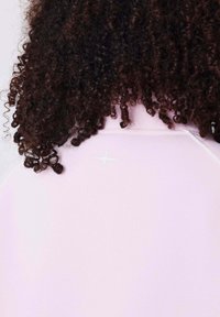 Lichtroze stof met een gladde textuur heeft een reflecterende sterdetail bij de kraag, aangevuld met donker, krullend haar.