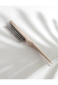 Pettine beige con manico appuntito e denti in metallo, caratterizzato da una superficie testurizzata. Design piatto, posto su uno sfondo chiaro.