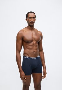 Tengerészkék boxeralsó puha textúrával és fehér "BOSS" logóval az derékpánton. Testhez simuló kivitel, combközépig érő hossz.