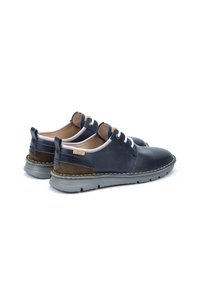Scarpe in pelle blu navy con dettagli in camoscio, lacci bianchi e suole in gomma grigia. Presentano un dettaglio di cucitura lungo la suola e un'etichetta del marchio.