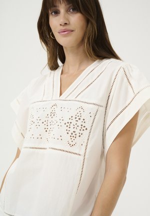 Witte blouse met een V-hals, voorzien van verfijnde uitsnijdingen aan de voorkant. Korte, vloeiende mouwen en een lichtgewicht stoftextuur.
