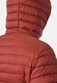 Gevoerde jas in roestkleur met een capuchon. Bevat een verticale quiltpatroon en een logo dat op de schouder is gedrukt. Gemaakt van lichtgewicht stof.