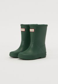 Bottes de pluie en caoutchouc vertes avec une semelle texturée, de hauteur courte et une étiquette logo. Présentent une finition lisse et un design à bout arrondi.