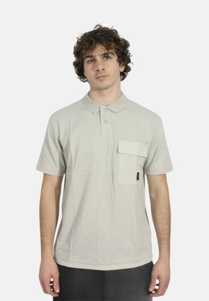 Polo shirt beige chiaro in cotone, dotata di taschino sul petto, patta con bottoni e maniche corte; texture liscia e vestibilità rilassata.