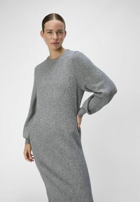 Abito grigio a maglia con maniche lunghe e gonfiate, scollo rotondo e dettagli a coste diagonali. Presenta un tessuto testurizzato e una silhouette slim e aderente.