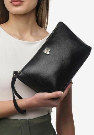 Zwarte leren clutch met een ritssluiting, voorzien van een gouden hardware accent aan de voorkant en een afneembare polsband. Soepele textuur.