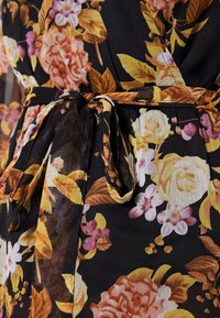 Schwarzes Blumenkleid mit pinken und gelben Rosen, grünen Blättern und einem gebundenen Gürtel. Hergestellt aus leichtem, strukturiertem Stoff.
