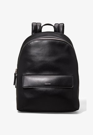 Zaino in pelle nera con texture liscia, parte superiore arrotondata, scomparto principale con zip e tasca frontale con un logo sottile.