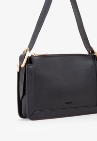 Borsa a tracolla in pelle nera con finitura texturizzata, caratterizzata da dettagli in metallo dorato, chiusura con zip e tracolla removibile.