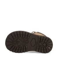 Suela de bota de goma marrón con un patrón de banda de rodadura profunda, agarres hexagonales y en forma de cruz, ligeramente desgastada, con una sección superior beige visible en el borde.