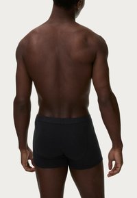 Schwarze Boxershorts aus einem weichen, dehnbaren Material, mit einem glatten Bund und einem sitzenden Design, das sich an den Körper anpasst.