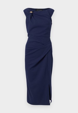 Tumši zila midi kleita bez piedurknēm ar asimetrisku drapējumu, sānu šķēlumu un dekoratīvu piespraudi pie apkakles kreisajā pusē.