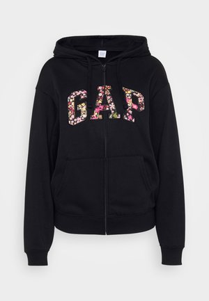 Čierna mikina na zips s kvetinovým logom "GAP". Má kapucňu, klokanie vrecká a rebrované manžety. Vyrobená z jemnej zmesi bavlny.