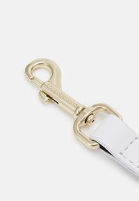 Vitt läderarmband med ett hölsterlås i guldmetall. Har en slät yta och en säker stängningsmekanism.