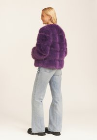 Purple faux fur jacket with a boxy cut, featuring a textured finish and long sleeves, paired with light blue flared jeans and black boots.