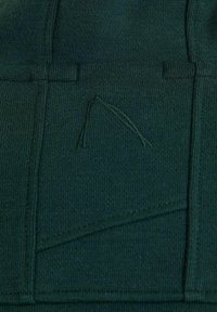 Tessuto lavorato a maglia verde scuro con fine coste, cuciture visibili e un motivo triangolare ricamato vicino al centro.