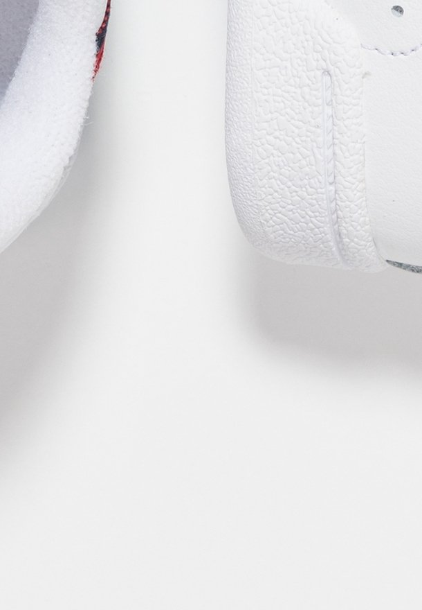 Vita sneakers har texturerat material, rund tå och kontrasterande innerfoder. En anmärkningsvärd detalj är en slät häl med subtilt sömnad.